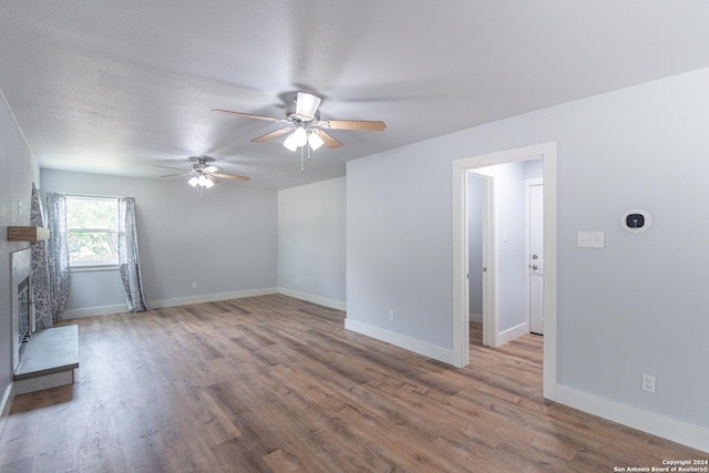 unfurnished living room featuring ceiling fan, hardwood / wood-style floors, and a textured ceiling