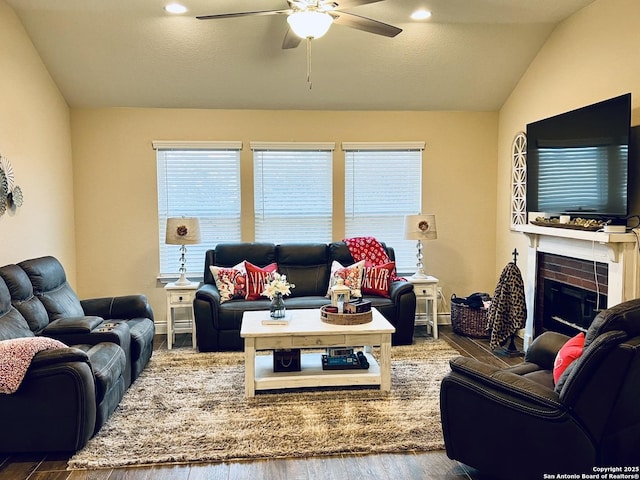 living room with vaulted ceiling, dark hardwood / wood-style flooring, ceiling fan, and a fireplace