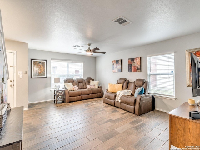 living room with ceiling fan and a textured ceiling