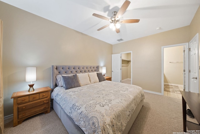 bedroom featuring ceiling fan, a spacious closet, light carpet, and a closet