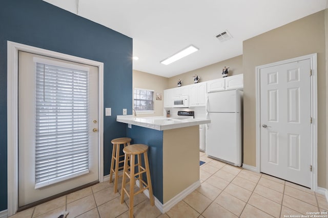 kitchen with a breakfast bar, white cabinetry, light tile patterned floors, kitchen peninsula, and white appliances