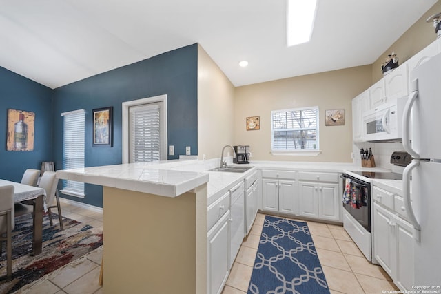 kitchen with sink, white appliances, tile counters, white cabinets, and kitchen peninsula