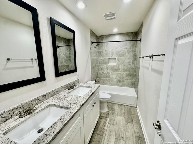 full bathroom with vanity, wood-type flooring, toilet, and tiled shower / bath