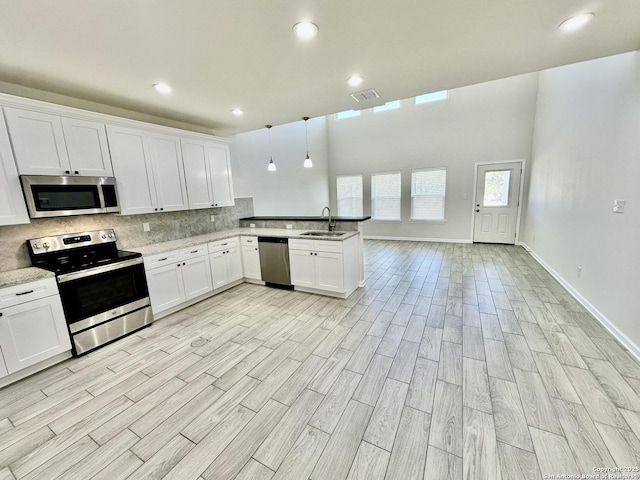 kitchen featuring appliances with stainless steel finishes, pendant lighting, sink, white cabinets, and kitchen peninsula