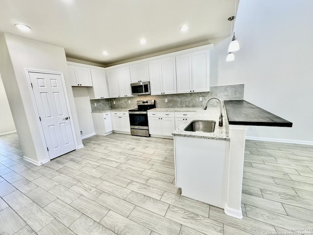 kitchen featuring appliances with stainless steel finishes, decorative light fixtures, white cabinetry, sink, and light stone countertops