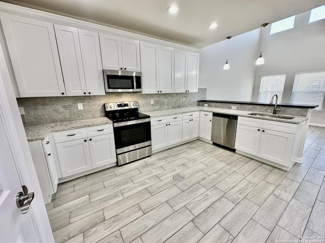 kitchen with sink, decorative light fixtures, stainless steel appliances, and white cabinets