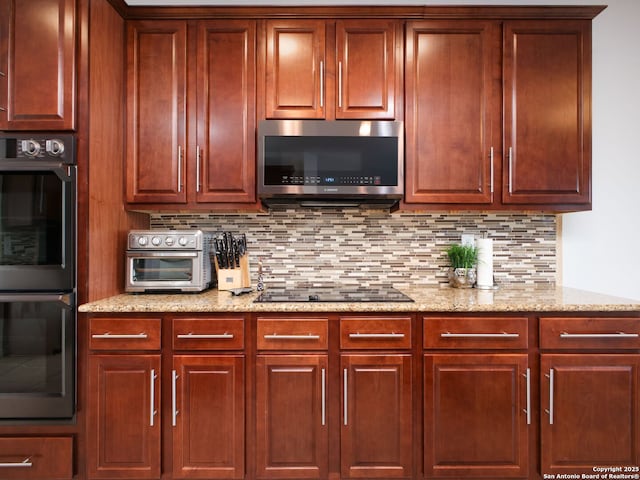 kitchen featuring double wall oven, black electric stovetop, light stone counters, and decorative backsplash