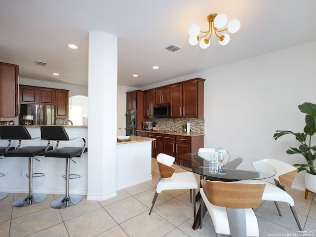 kitchen with light stone counters, appliances with stainless steel finishes, light tile patterned floors, and backsplash