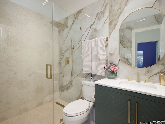 bathroom with vanity, a shower with door, tile walls, and toilet