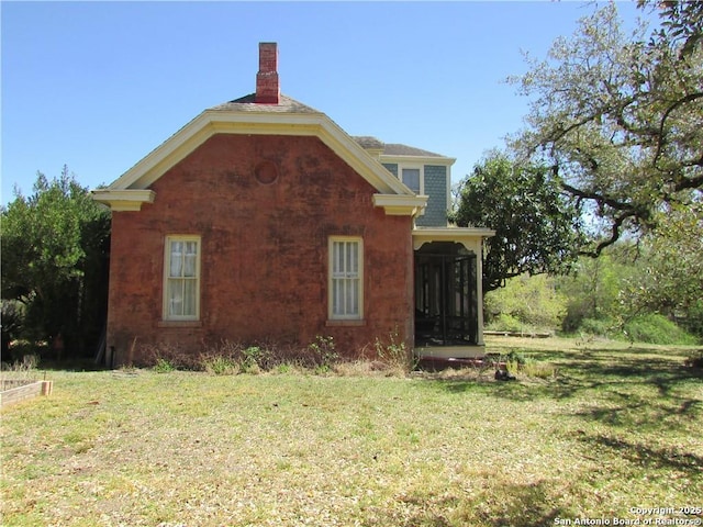 view of home's exterior with a sunroom and a yard