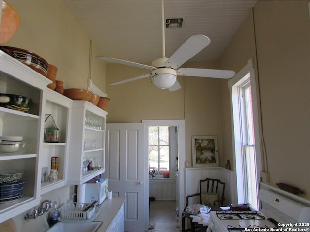 kitchen with sink, white range with gas cooktop, ceiling fan, and a towering ceiling