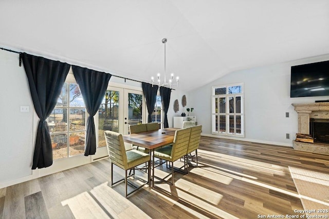 dining space featuring lofted ceiling, hardwood / wood-style floors, french doors, and a chandelier