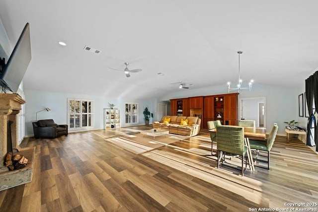 living room featuring lofted ceiling, hardwood / wood-style flooring, and ceiling fan with notable chandelier