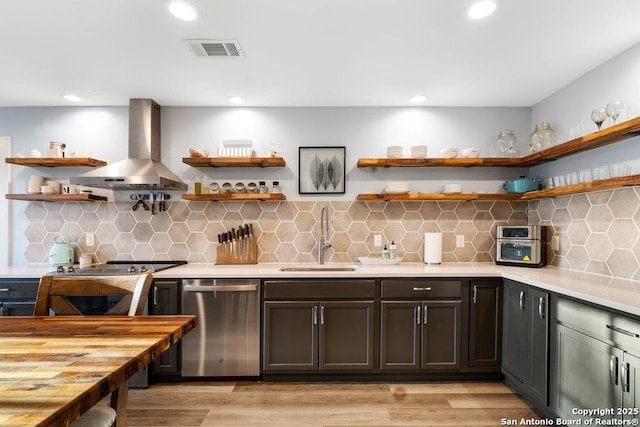 kitchen featuring tasteful backsplash, sink, dishwasher, and wall chimney exhaust hood