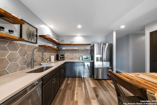 kitchen featuring tasteful backsplash, wood-type flooring, appliances with stainless steel finishes, and sink