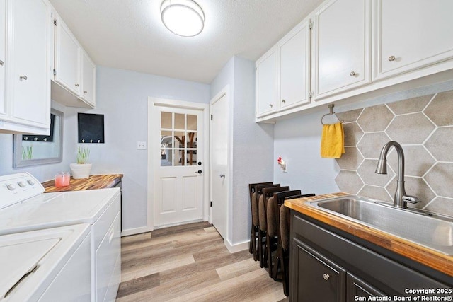 clothes washing area featuring cabinets, sink, independent washer and dryer, and light wood-type flooring