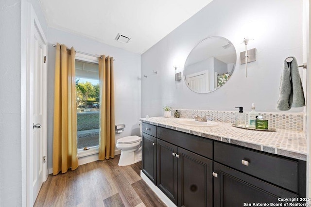 bathroom with vanity, backsplash, hardwood / wood-style floors, and toilet