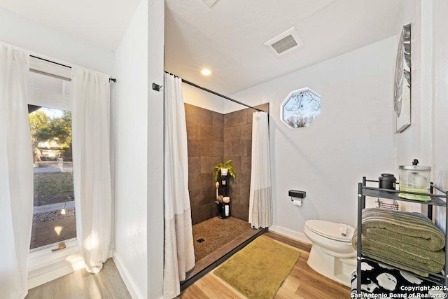 bathroom featuring wood-type flooring, toilet, and a shower with shower curtain