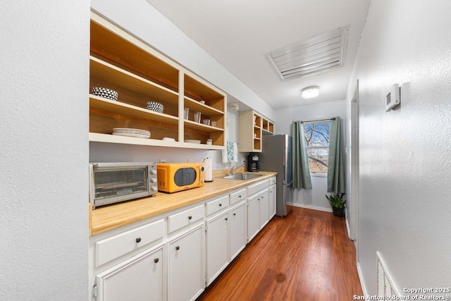 kitchen featuring stainless steel fridge, sink, white cabinets, and dark hardwood / wood-style flooring