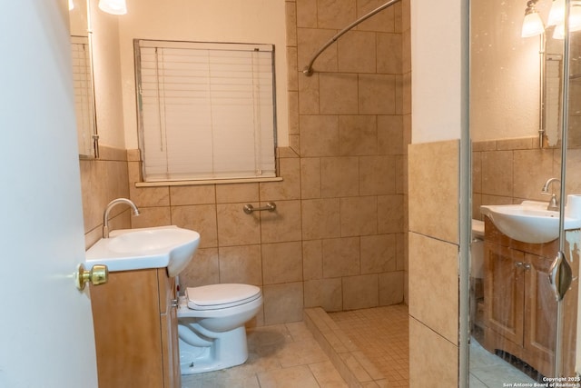 bathroom with tile patterned flooring, a tile shower, tile walls, and vanity