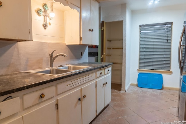 kitchen featuring white cabinetry, backsplash, sink, and light tile patterned floors