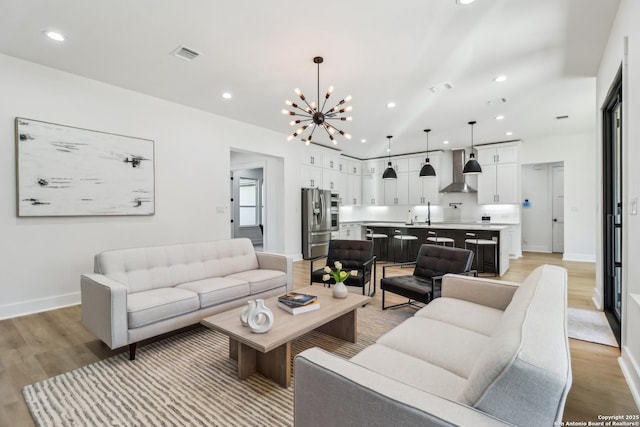 living area with light wood-style flooring, recessed lighting, visible vents, baseboards, and an inviting chandelier