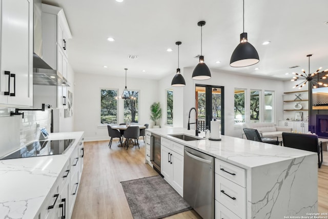 kitchen with an inviting chandelier, light wood-style floors, a sink, dishwasher, and black electric cooktop