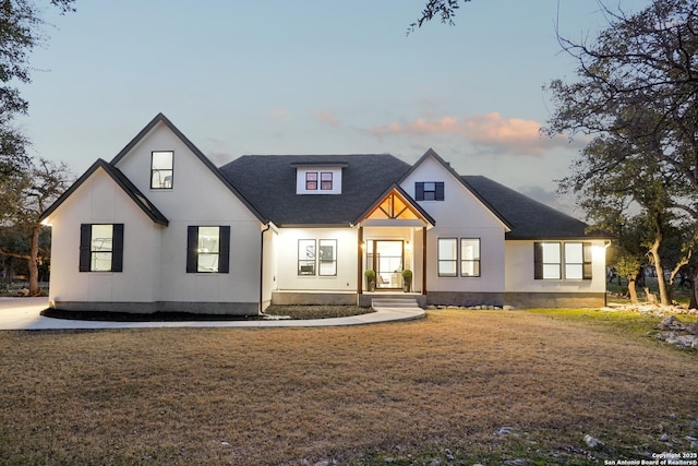 modern farmhouse style home featuring a yard and a shingled roof