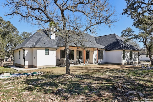 back of property featuring stucco siding, a patio area, a chimney, and roof with shingles