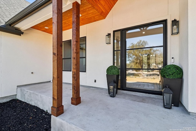 doorway to property with roof with shingles and stucco siding