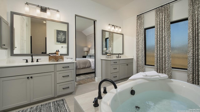 bathroom with a tub to relax in, vaulted ceiling, and vanity