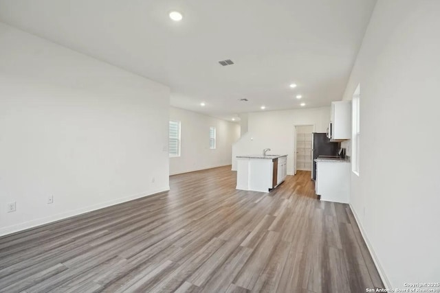 unfurnished living room with light hardwood / wood-style floors and sink