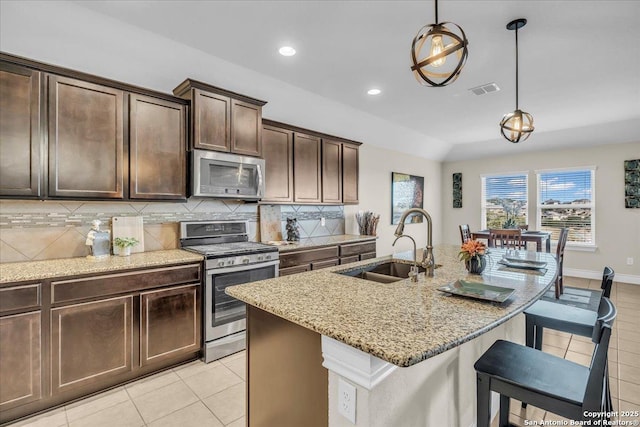 kitchen with sink, tasteful backsplash, hanging light fixtures, stainless steel appliances, and light stone countertops