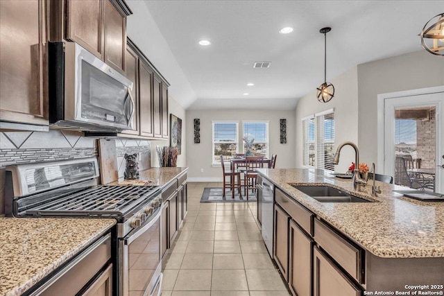 kitchen with sink, dark brown cabinets, appliances with stainless steel finishes, an island with sink, and pendant lighting