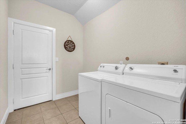 laundry area featuring light tile patterned floors, washer and dryer, and a textured ceiling