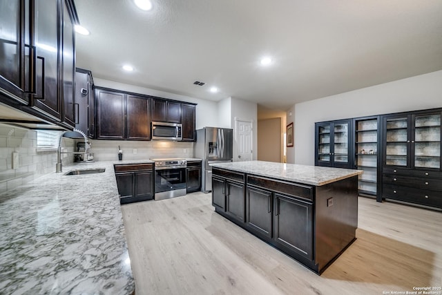 kitchen with sink, decorative backsplash, stainless steel appliances, and a kitchen island