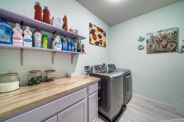 clothes washing area featuring washing machine and clothes dryer, light hardwood / wood-style floors, and a textured ceiling