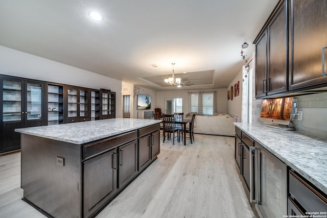 kitchen featuring dark brown cabinets, light hardwood / wood-style floors, a raised ceiling, and a kitchen island