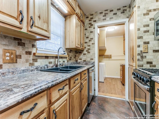 kitchen featuring appliances with stainless steel finishes, sink, light stone counters, dark wood-type flooring, and washer and clothes dryer