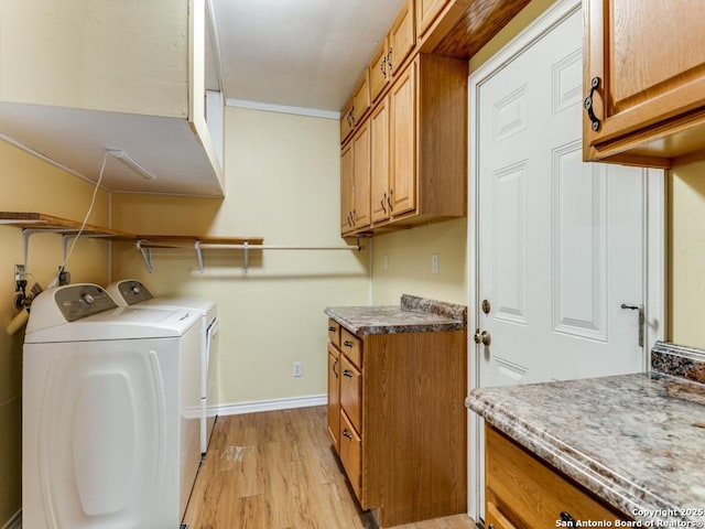 washroom with cabinets, washing machine and dryer, and light hardwood / wood-style flooring