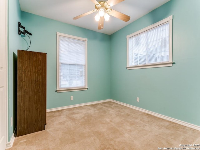 carpeted spare room featuring ceiling fan