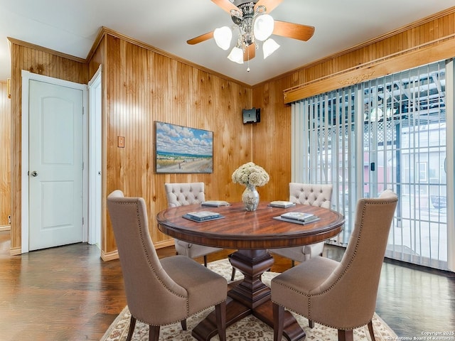 dining room with wooden walls, ornamental molding, and dark hardwood / wood-style floors