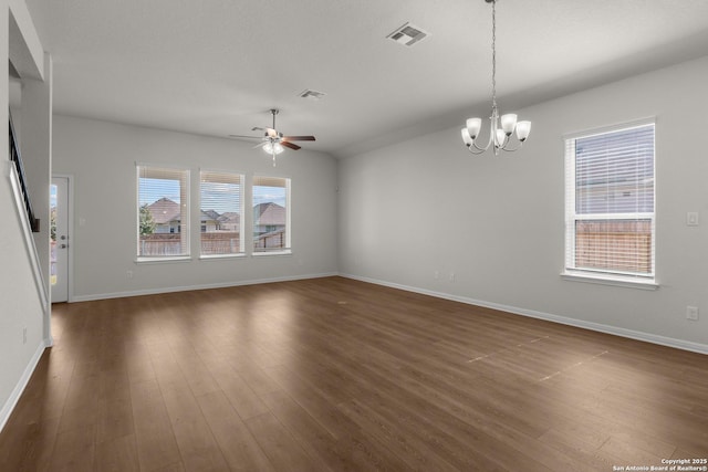 spare room featuring ceiling fan with notable chandelier, dark hardwood / wood-style floors, and a healthy amount of sunlight