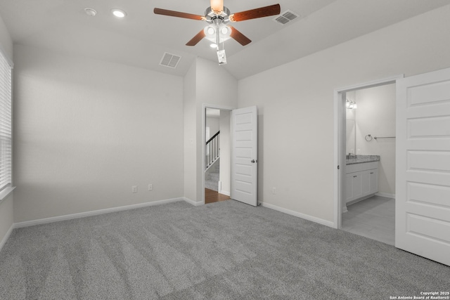 unfurnished bedroom featuring ceiling fan, connected bathroom, vaulted ceiling, and light carpet