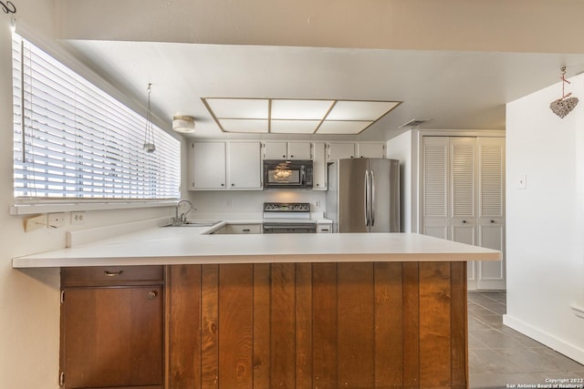 kitchen featuring electric range oven, sink, white cabinets, stainless steel fridge, and kitchen peninsula