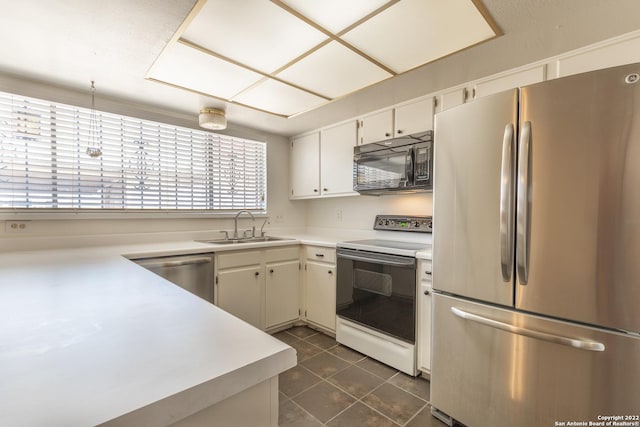 kitchen with stainless steel appliances, white cabinetry, sink, and dark tile patterned flooring