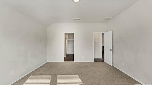 unfurnished bedroom with a closet, a spacious closet, and carpet flooring