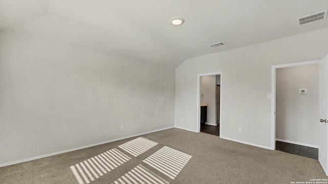 carpeted spare room with vaulted ceiling