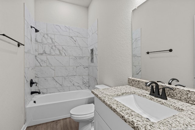 full bathroom with vanity, hardwood / wood-style floors, tiled shower / bath, and toilet