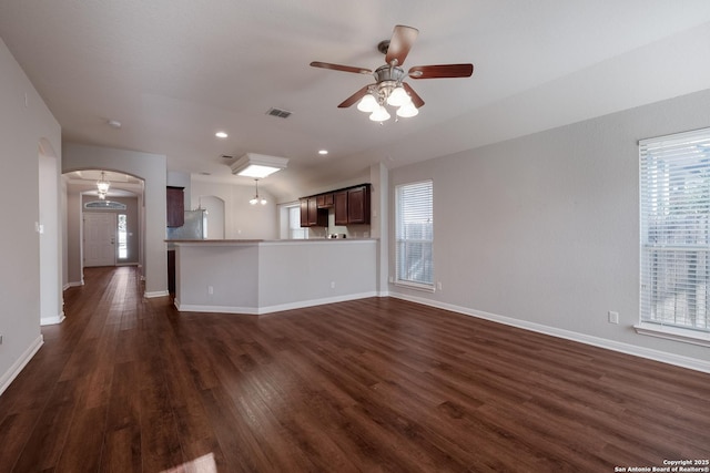 unfurnished living room featuring plenty of natural light, dark wood-type flooring, and ceiling fan